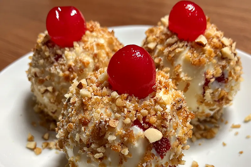 A close-up of the cherry bombs being dipped in chocolate ganache, showcasing the process of creating this festive dessert.