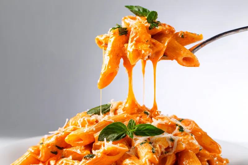 Cooking process of creamy vodka penne pasta in a skillet.