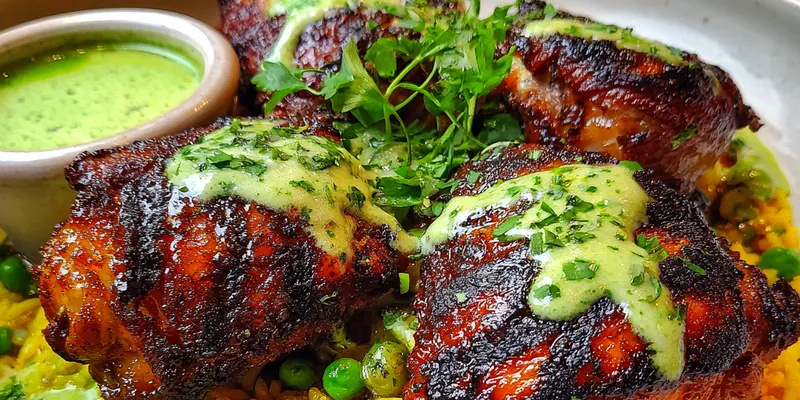 A vibrant dish of Grilled Peruvian Chicken served with fluffy rice, garnished with cilantro and lemon wedges.